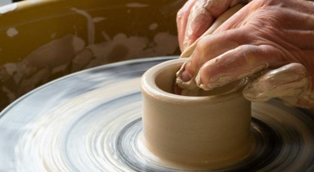Person working on potters wheel as a work in progress